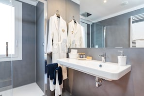 A modern bathroom with a large mirror, white sink, and two white robes hanging on a rack. - Venice Heaven Apartments Biennale (Venice)