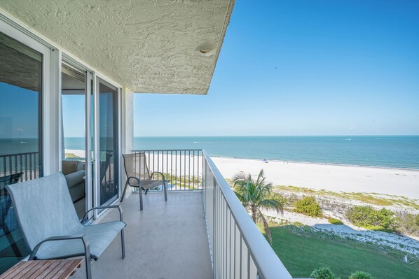 A balcony with a view of the beach and ocean.