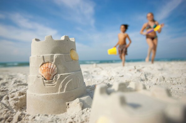 A sandy beach with a sandcastle featuring a seashell.