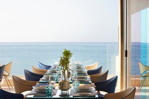 Une table à manger dressée pour deux personnes, avec vue sur l’océan.