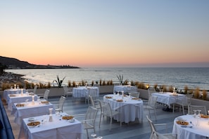 An outdoor dining area with tables set for a meal, overlooking a body of water. - I Resort Beach Hotel & Spa (Hersonissos)