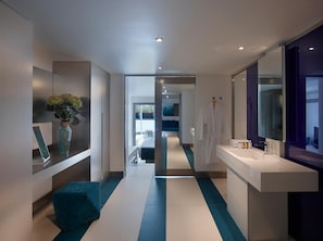 Un baño de hotel moderno con un espejo grande, un lavabo y una zona de ducha.