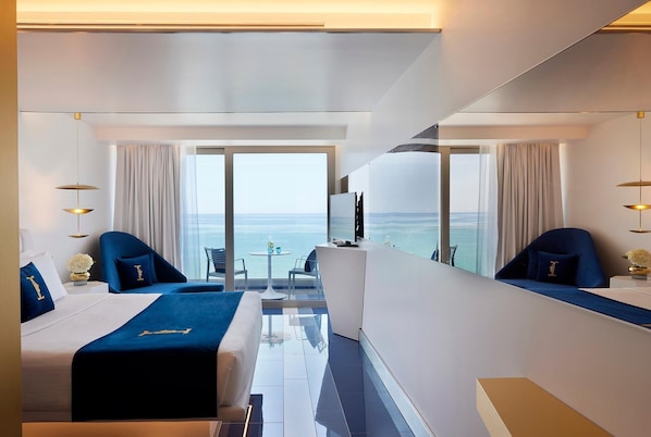 Una habitación de hotel moderna con una cama, un escritorio y vista al océano.