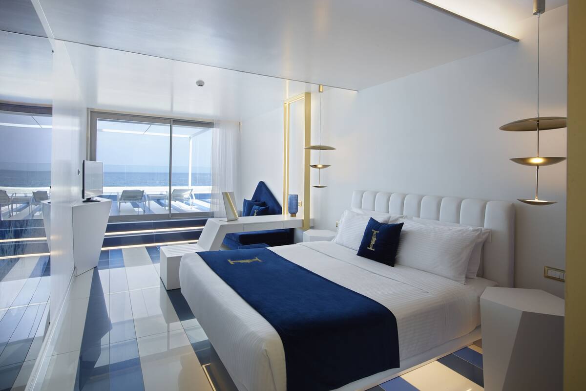 Une chambre moderne avec un grand lit, un bureau et une vue sur l’océan.