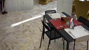 A modern hotel lobby with a marble floor, a reception desk, a dining area with a red table, and a comfortable seating area with a yellow armchair. - Di Palma Suite Museum (Naples)