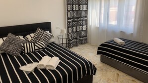 A hotel room with a large bed, a smaller bed, a patterned curtain, and a window with sheer curtains. - Di Palma Suite Museum (Naples)