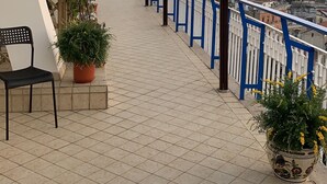 A balcony with a tiled floor, blue railing, potted plants, and a view of a cityscape. - Di Palma Suite Museum (Naples)