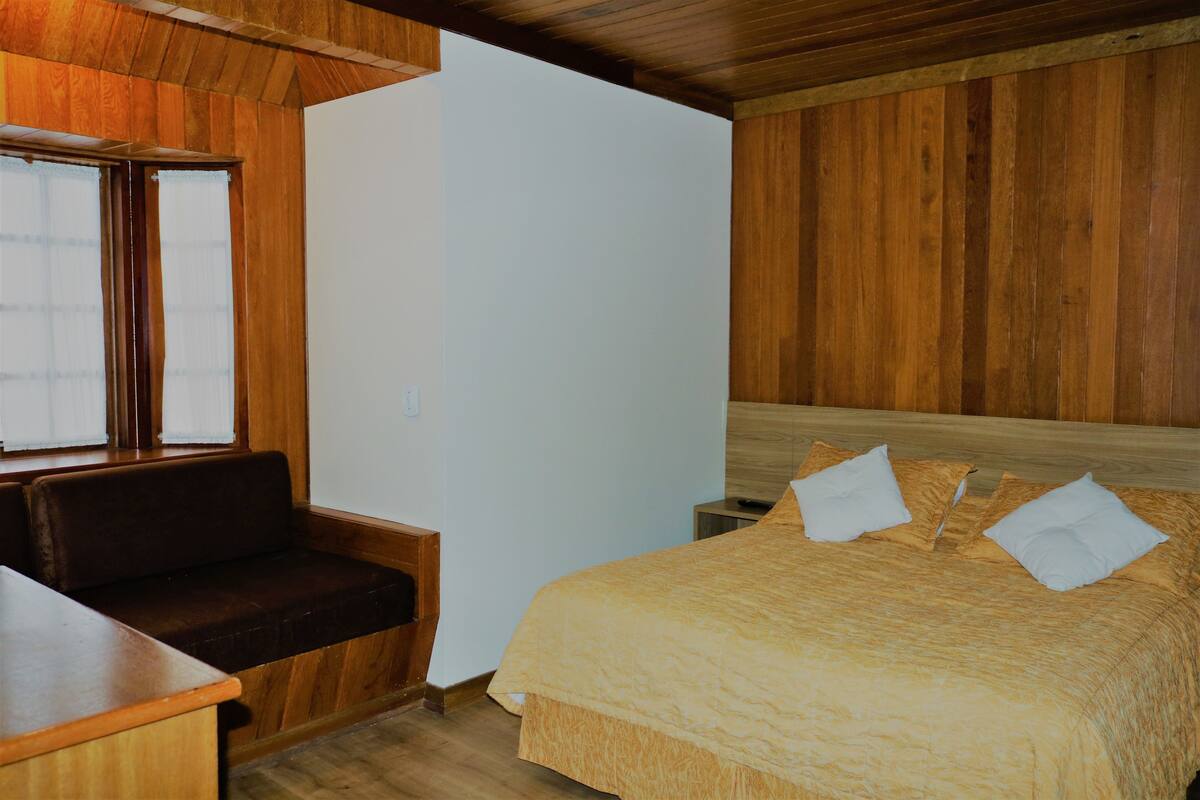Ein Zimmer mit einem Bett, einer Bank und einem kleinen Tisch.