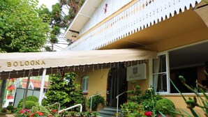 Un bâtiment sur lequel on peut lire l’inscription « BOLOGNE », et un espace extérieur abrité, agrémenté de plantes et de fleurs en pot.