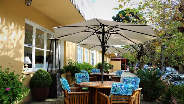 Une terrasse extérieure avec des tables et des chaises en bois, de grands parasols et des plantes en pot.