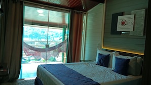 A bedroom with a bed, curtains, and a view of a traditional structure outside. - Summit Lago Hotel (Lambari)