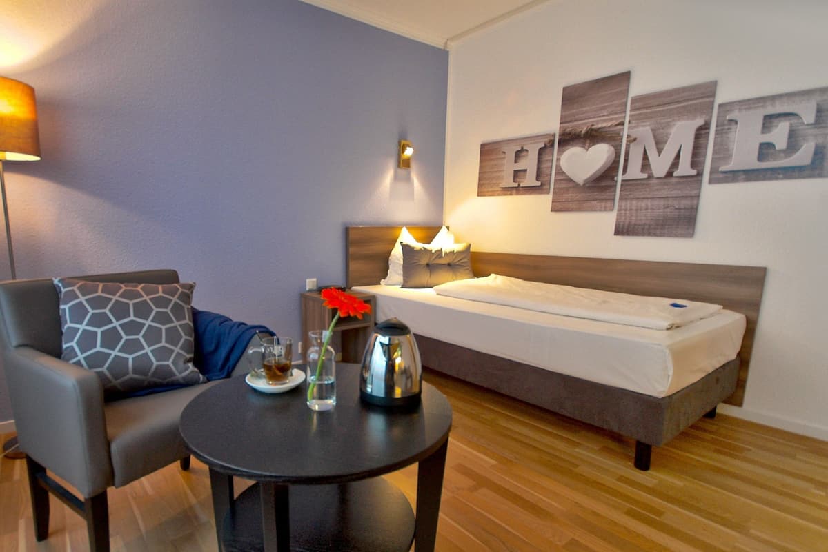 Un dormitorio moderno con una cama, una silla, una mesita con una flor y una pared que dice 'HOME'.