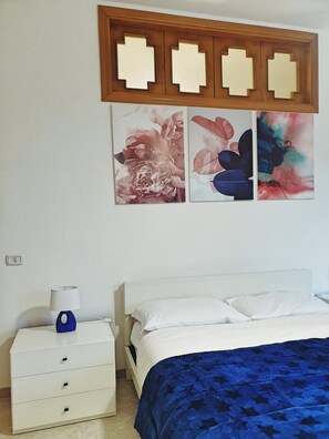 Un dormitorio con cama, mesita de noche, lámpara y decoración en la pared.