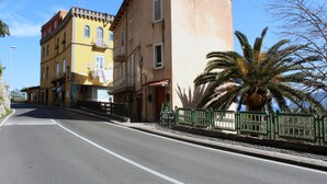 A street with buildings, a palm tree, and a green fence. - Casa Athena (Sorrento)
