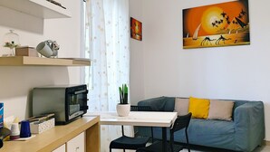A living area with a dining table, chairs, a sofa, a TV, and a painting on the wall. - Casa Athena (Sorrento)