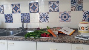 A kitchen with a granite countertop, a sink, and a weighing scale. - Casa Athena (Sorrento)