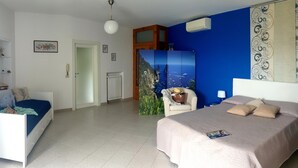 A bedroom with a bed, a chair, a radiator, and a door. - Casa Athena (Sorrento)