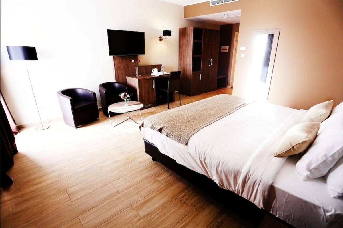 A modern hotel room with a large bed, a desk, a chair, and a television.
