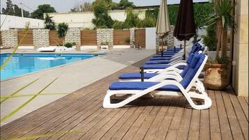 Una piscina al aire libre, sombrillas, tumbonas