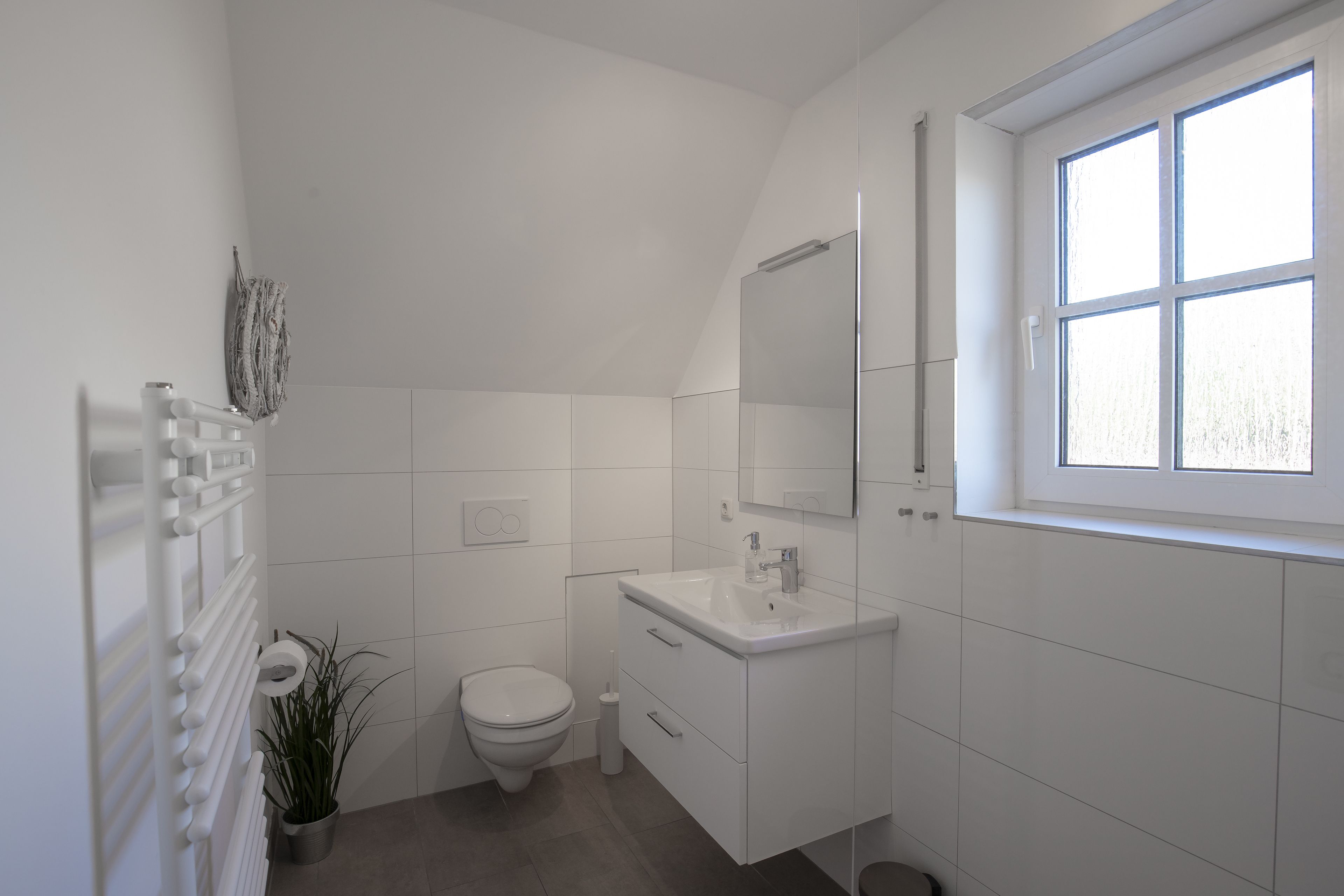 A modern bathroom with a toilet, sink, and mirror.