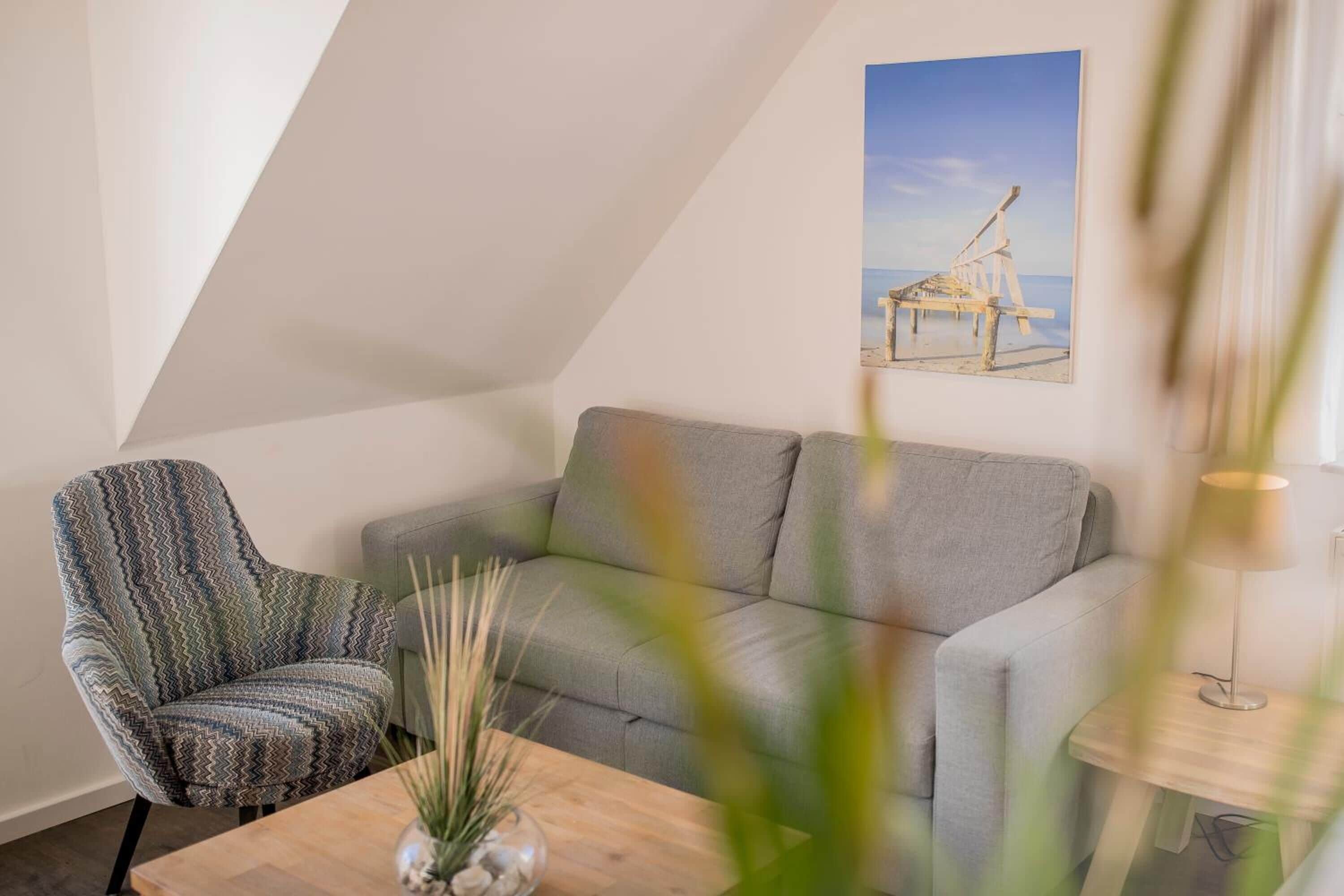 A modern living room with a grey sofa, a patterned armchair, and a wooden coffee table.