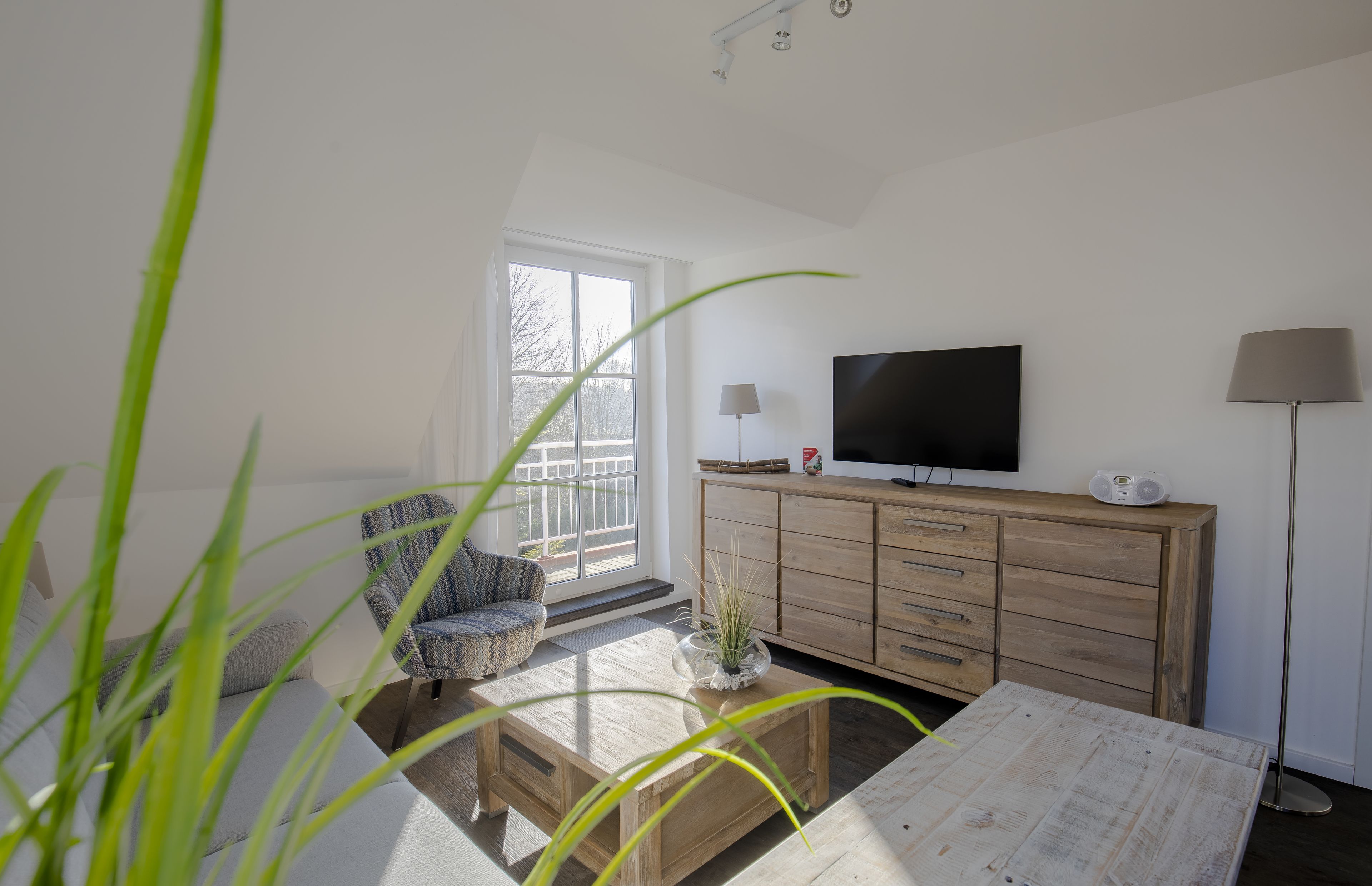 Una sala de estar con televisor, mueble de madera y un sillón.