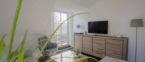Una sala de estar con televisor, mueble de madera y un sillón.