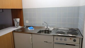 A compact kitchen with a sink, stove, and a coffee maker. - Popular and centrally located residential building in St. (St. Moritz)