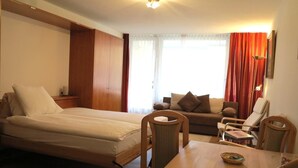 A room with a bed, a sofa, a dining table, and chairs. - Popular and centrally located residential building in St. (St. Moritz)