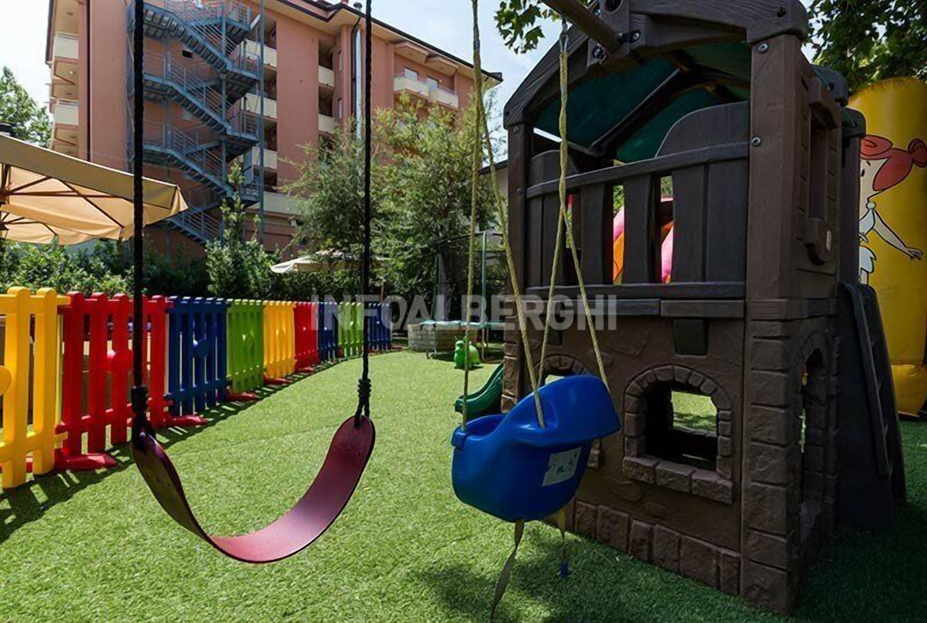 A children's play area with a swing set, a small playhouse, and a fenced play area.