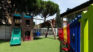 A children's play area with a slide, climbing structures, and a fenced play zone. - Hotel Turquoise (Cesenatico)