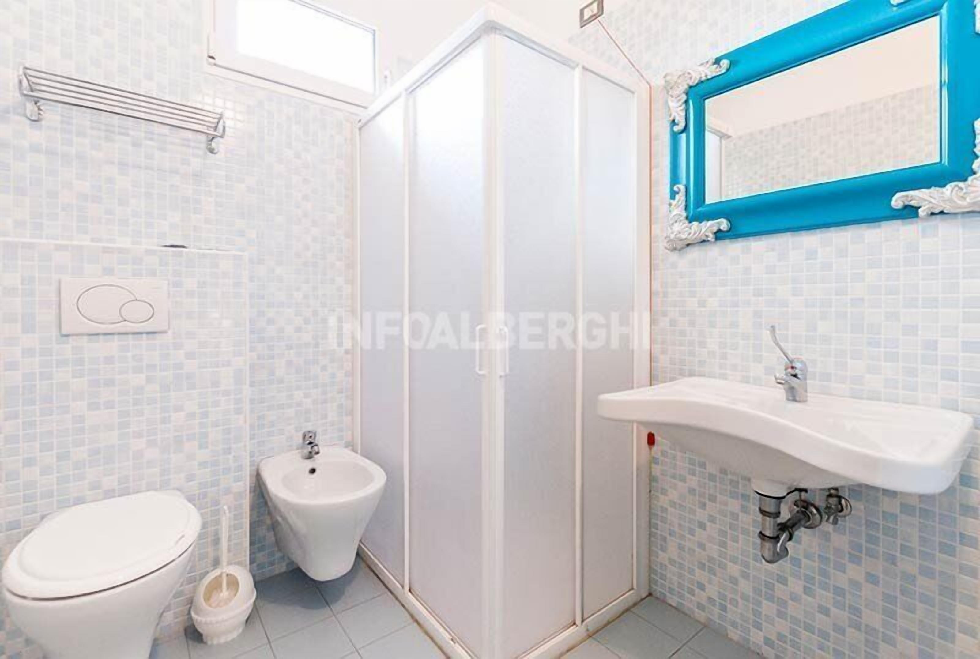 A bathroom with a toilet, bidet, and a sink.