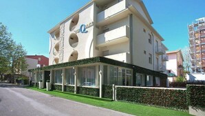 A multi-story hotel with a modern design, featuring balconies and a covered entrance area. - Hotel Turquoise (Cesenatico)