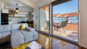 A modern living room with a sofa, a dining area with chairs, and a sliding glass door leading to an outdoor patio. - Villa M (Split)