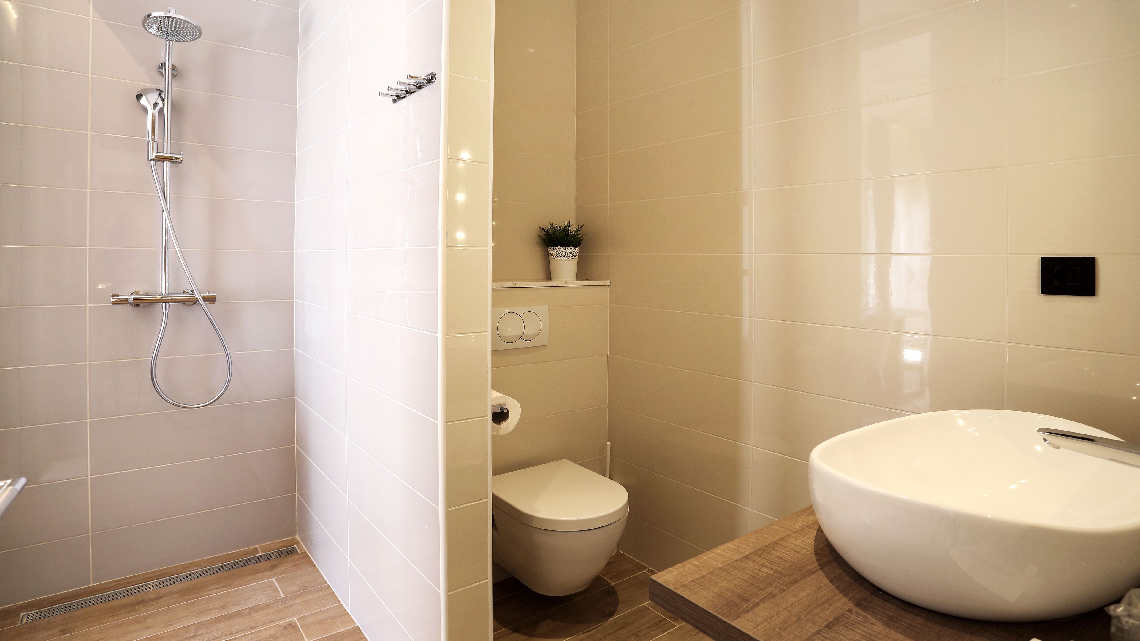 Et badeværelse med bruser, toilet og vask.
