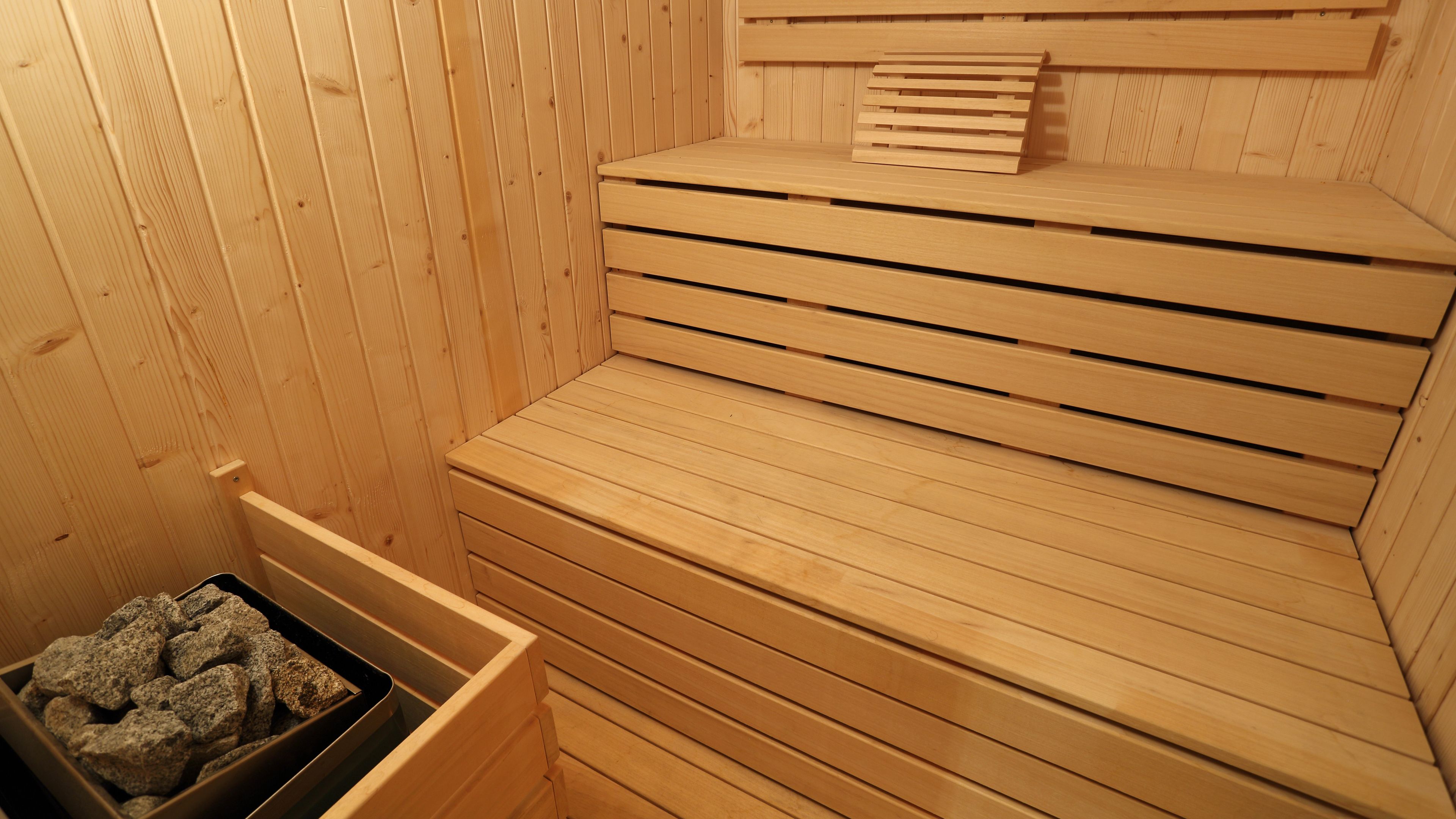 A wooden sauna with benches and a stone tray.