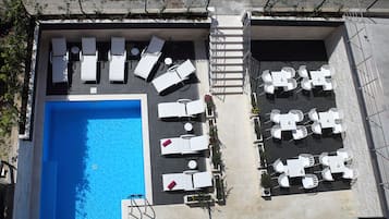 Una piscina al aire libre de temporada, sillones reclinables de piscina