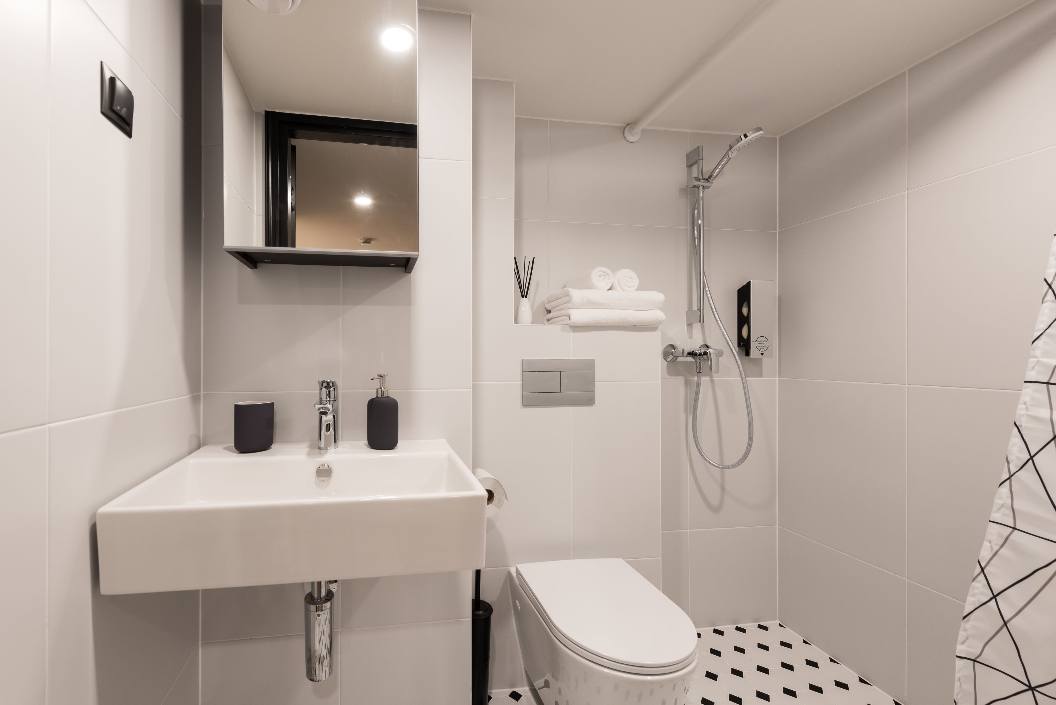 A modern bathroom with a white sink, a toilet, and a shower.