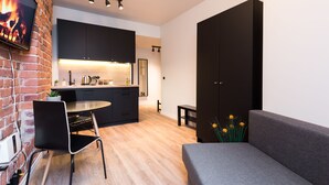 A modern kitchen with black cabinets, a dining area with a round table and chairs, and a grey sofa. - Hilltop Apartments City Centre (Tallinn)