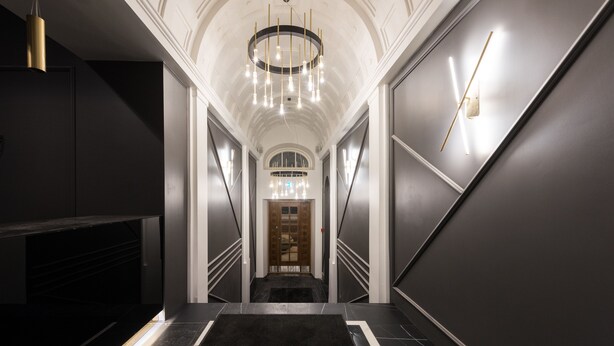 A modern hotel lobby with a grand staircase, a chandelier, and a reception desk. - Hilltop Apartments City Centre (Tallinn)