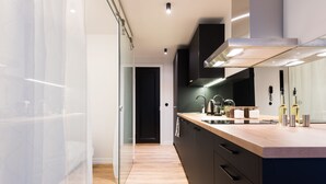 A modern kitchen with a wooden countertop, stainless steel appliances, and a glass partition. - Hilltop Apartments City Centre (Tallinn)