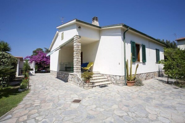 A white building with a stone facade, a covered porch, and a cactus in the garden. - Villa Leo (Portoferraio)