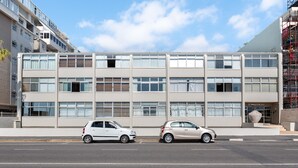 A modern multi-story building with a flat facade, large windows, and a visible entrance with a sign. - Sandringham 23 (Cape Town)