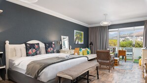 A bedroom with a large bed, a bench, a chair, a dresser, and a view of the outside. - Sandringham 23 (Cape Town)