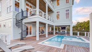 Ein mehrstöckiges Haus mit einer großen Terrasse, einem Pool und Sitzgelegenheiten im Freien.