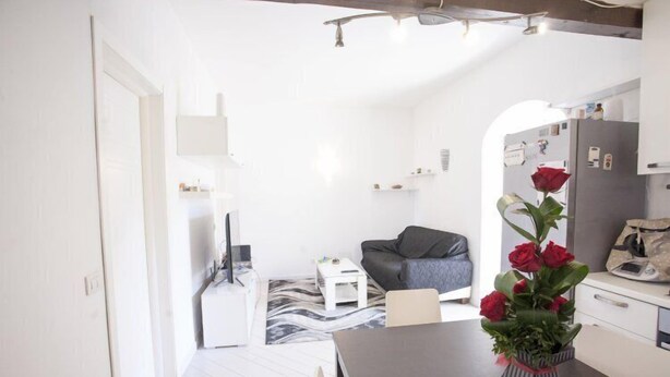 A modern kitchen with white cabinets, a dining table, and a vase with red roses.