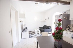 A modern kitchen with white cabinets, a dining table, and a vase with red roses.