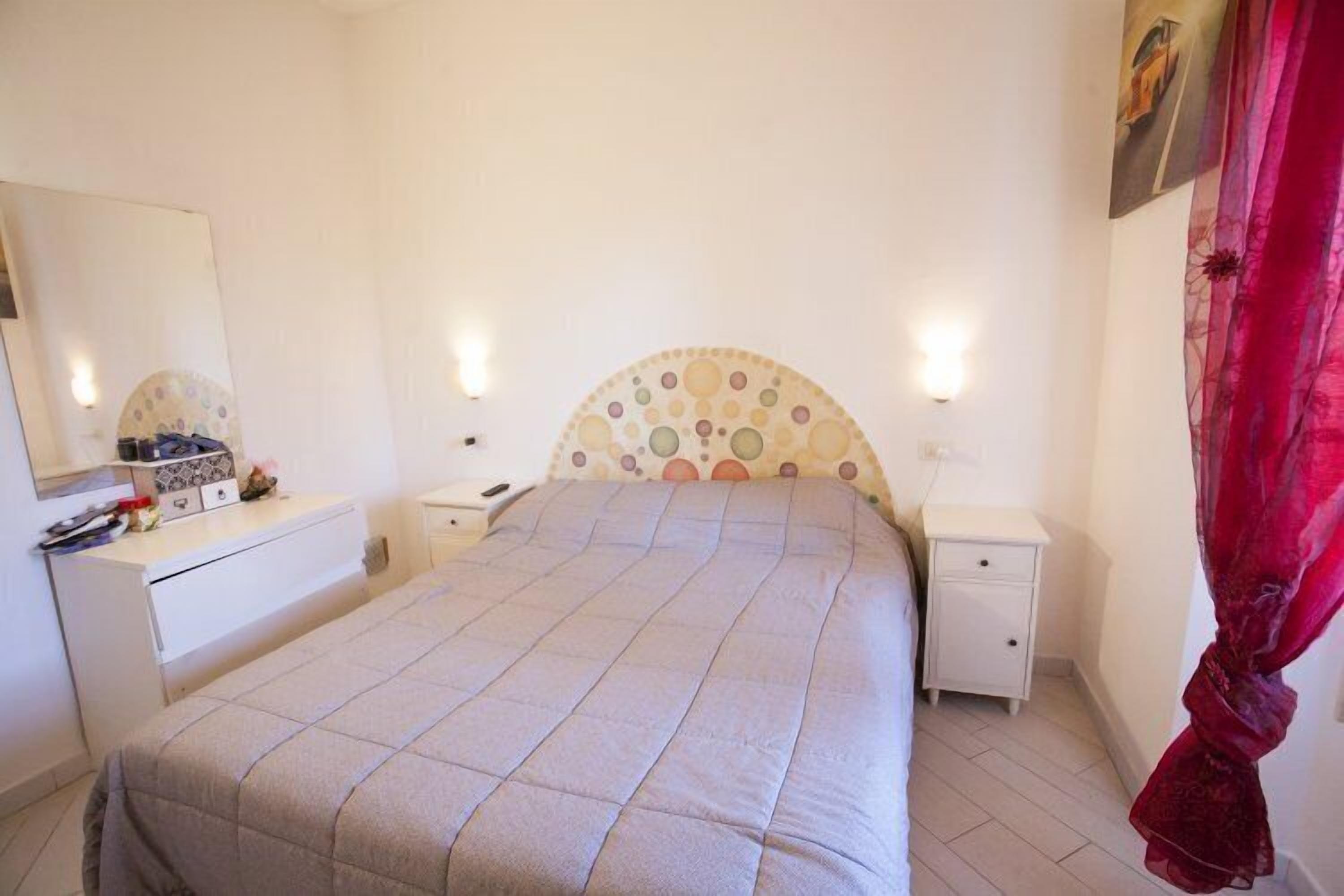 A bedroom with a bed, bedside tables, a dresser, and a mirror.