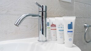 A bathroom with a chrome faucet, a white sink, and three toiletry bottles labeled with different hair care products. - Italianway Comfort - Bligny 19 B (Milan)