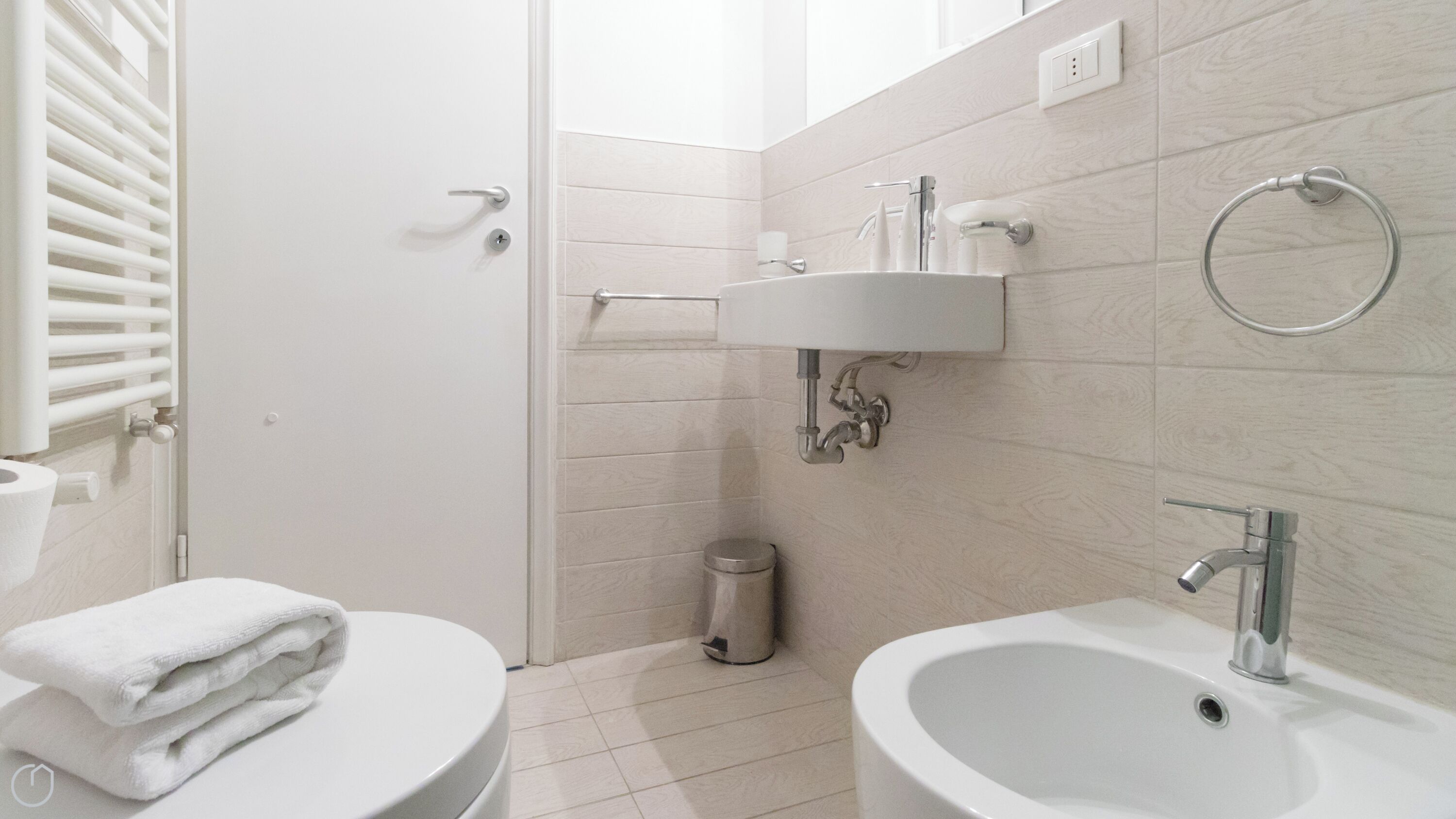 Une salle de bain moderne équipée de toilettes, d’un bidet, d’un lavabo et d’une pile de serviettes.